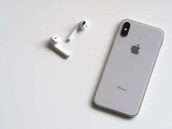 Sleek iPhone and AirPods on light background, minimalist tech lifestyle aesthetic.