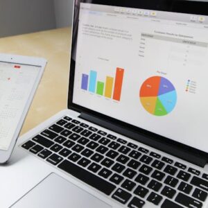 Modern laptop and tablet on desk, displaying colorful graphs for business analysis.